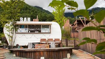 A white RV with a wooden deck, surrounded by a wooden fence and gravel paths.