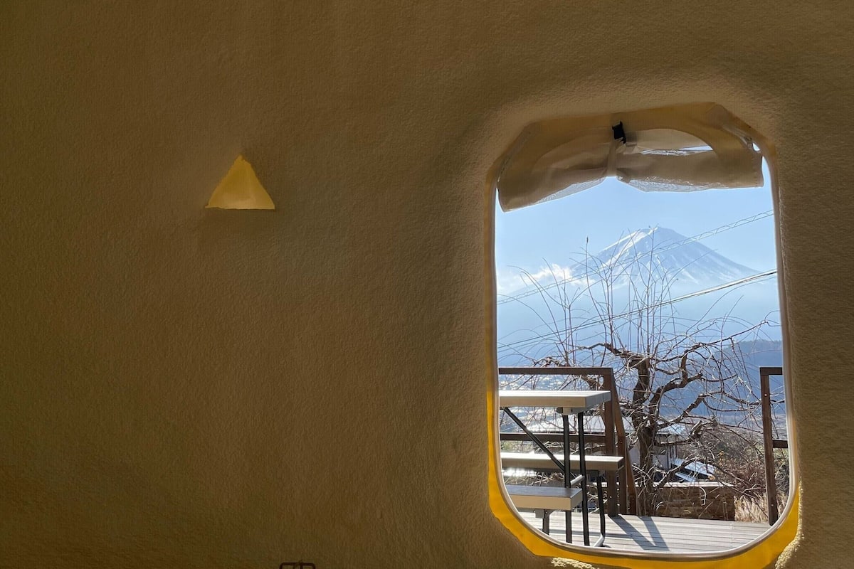 Vista desde una ventana que muestra un edificio con una montaña al fondo.
