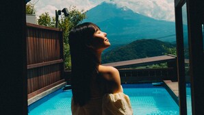 A person standing by a pool with a mountainous landscape in the background. - Dot Glamping Fujisan (Fujikawaguchiko)