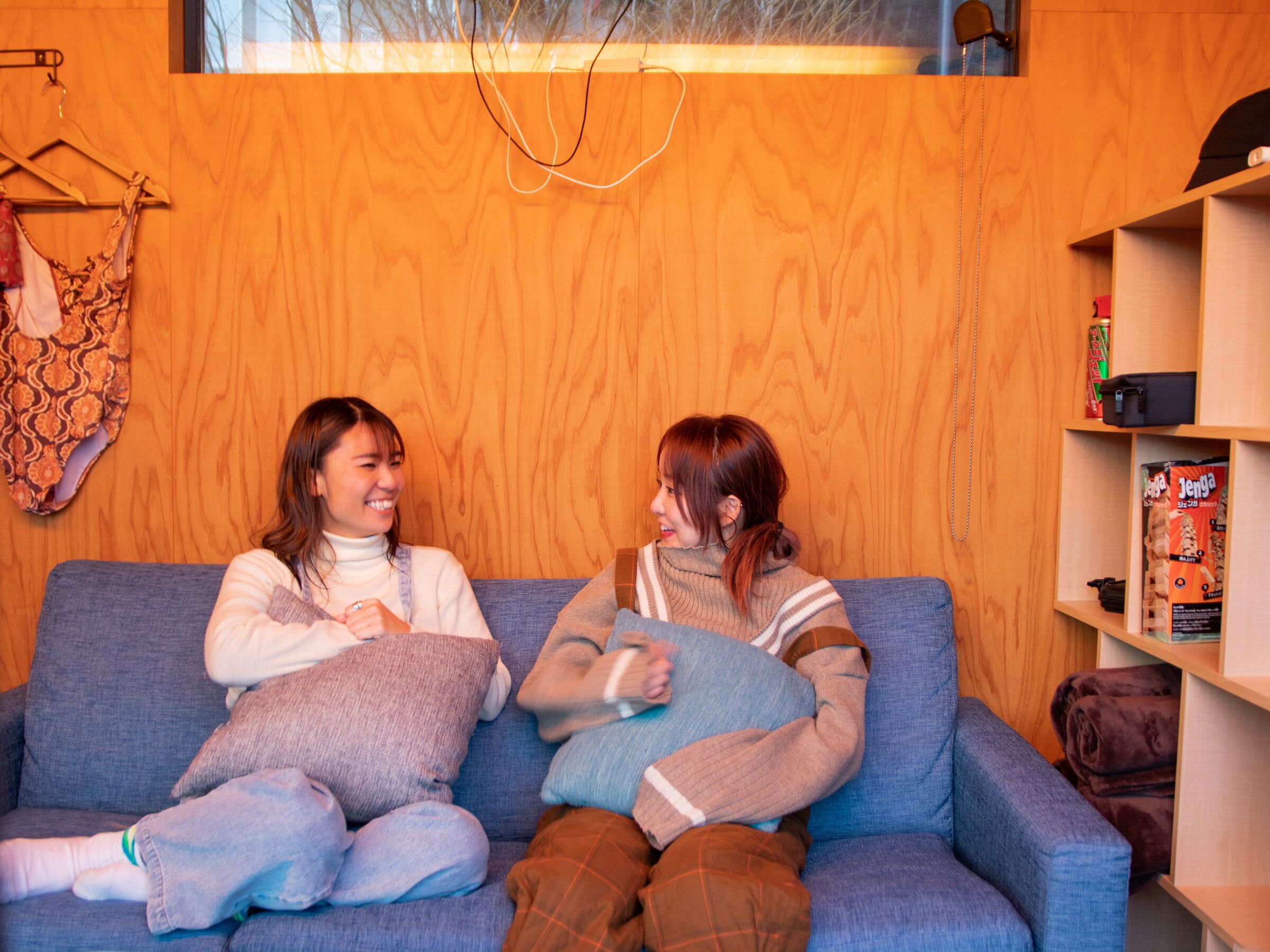 A cozy room with a wooden wall, a blue sofa, and a shelf with items.