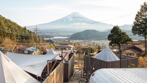 A view of a mountain with a town in the foreground, featuring tents and wooden fences. - Dot Glamping Fujisan (Fujikawaguchiko)