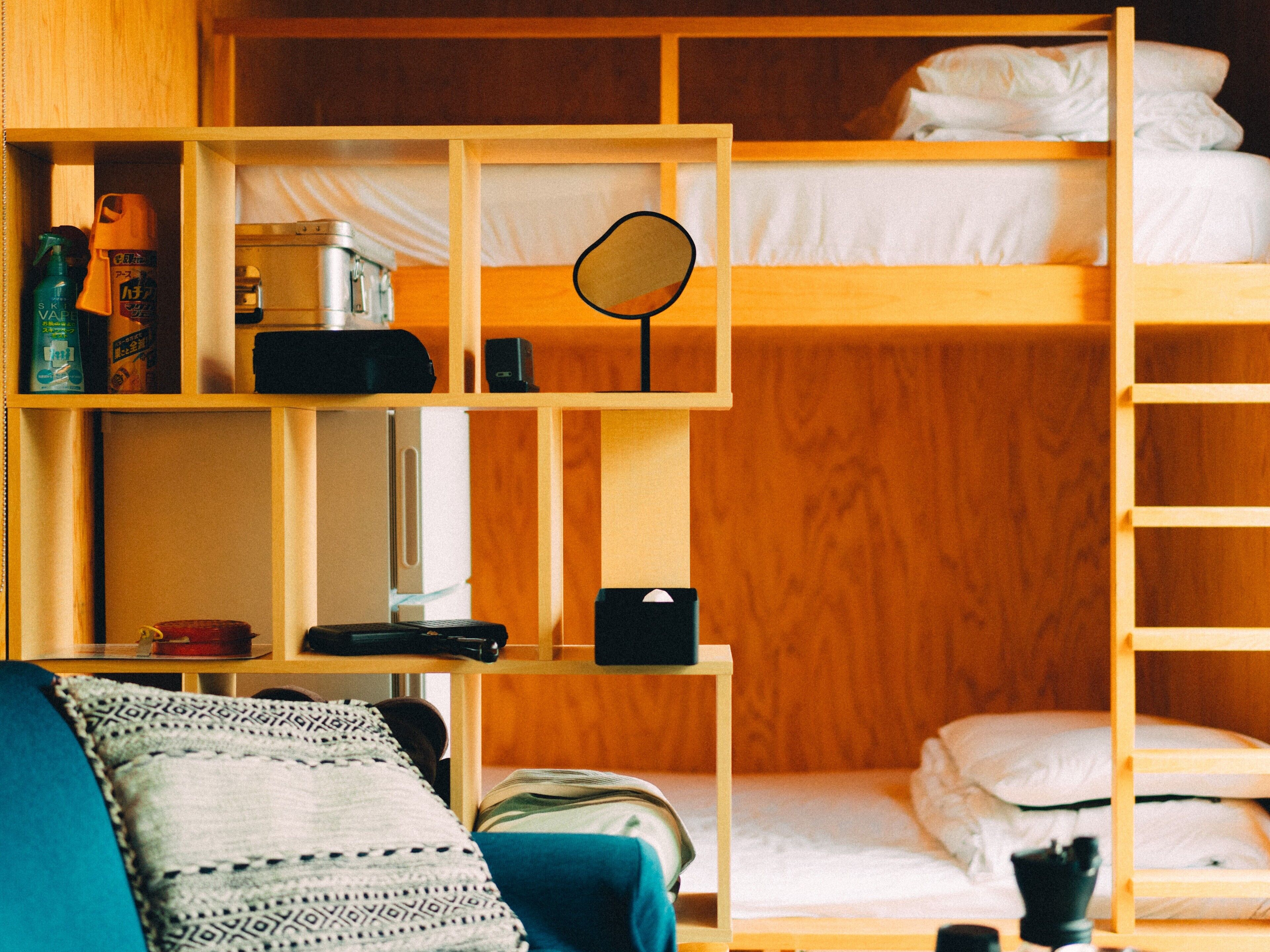 A bunk bed room with a desk, shelves, and a mirror.