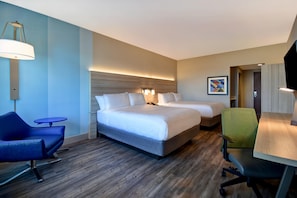 Ein Hotelzimmer mit zwei Betten, einem Schreibtisch, einem Stuhl und einem Fernseher.