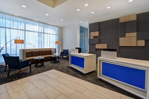 A modern hotel lobby with a reception desk, seating area, and large windows. - Holiday Inn Express And Suites Galveston Beach (Galveston)
