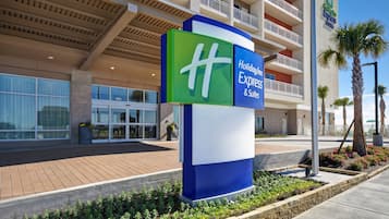 A Holiday Inn Express building with a prominent sign, large windows, and a landscaped area with plants and a palm tree.