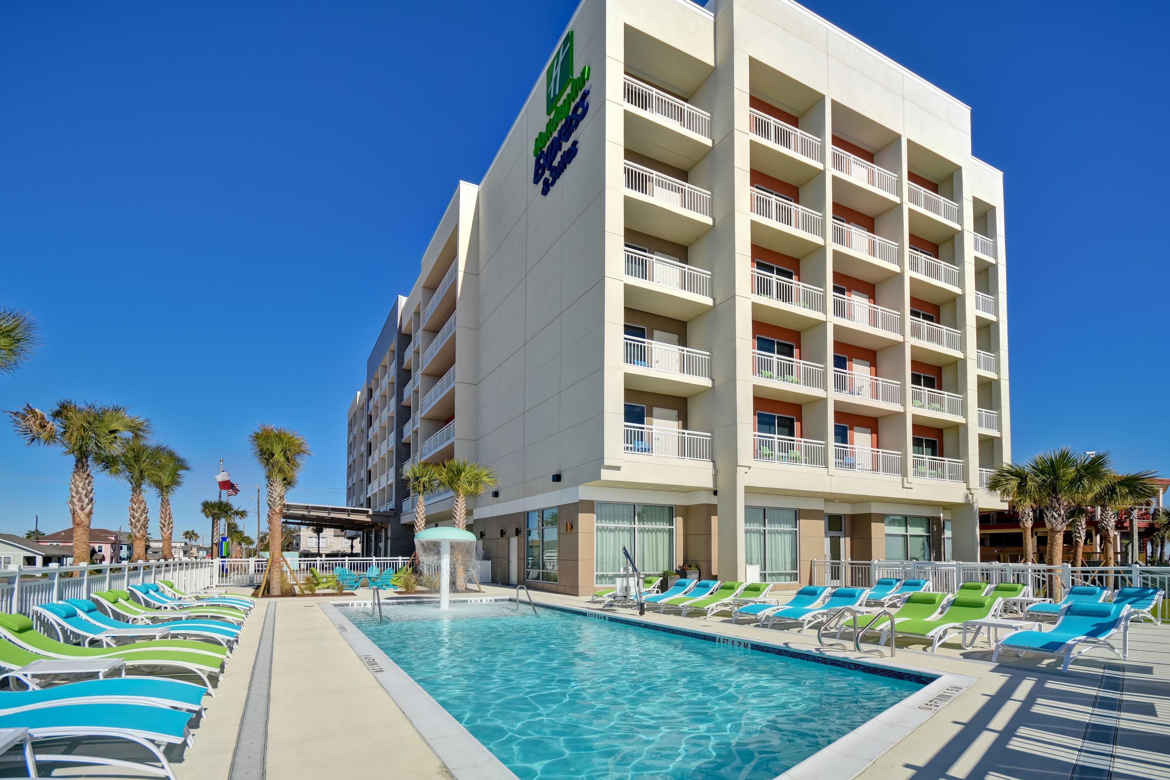 A hotel with a swimming pool, multiple balconies, and palm trees.