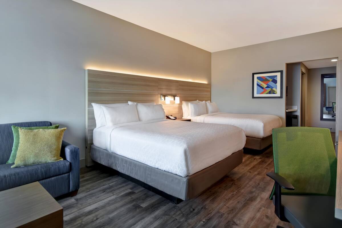 Ein Hotelzimmer mit zwei Betten, einem Schlafsofa, einem Schreibtisch und einem Sessel.