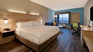 A hotel room with a large bed, bedside tables, a desk, a chair, and a view of the ocean. - Holiday Inn Express And Suites Galveston Beach (Galveston)