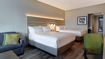 Une chambre d’hôtel avec deux lits, un canapé, un bureau et une chaise.