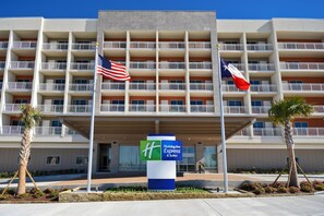 Ein Holiday Inn Express & Suites Gebäude mit modernem Design, mit Balkonen und einer gut sichtbaren amerikanischer und Texas Flagge.
