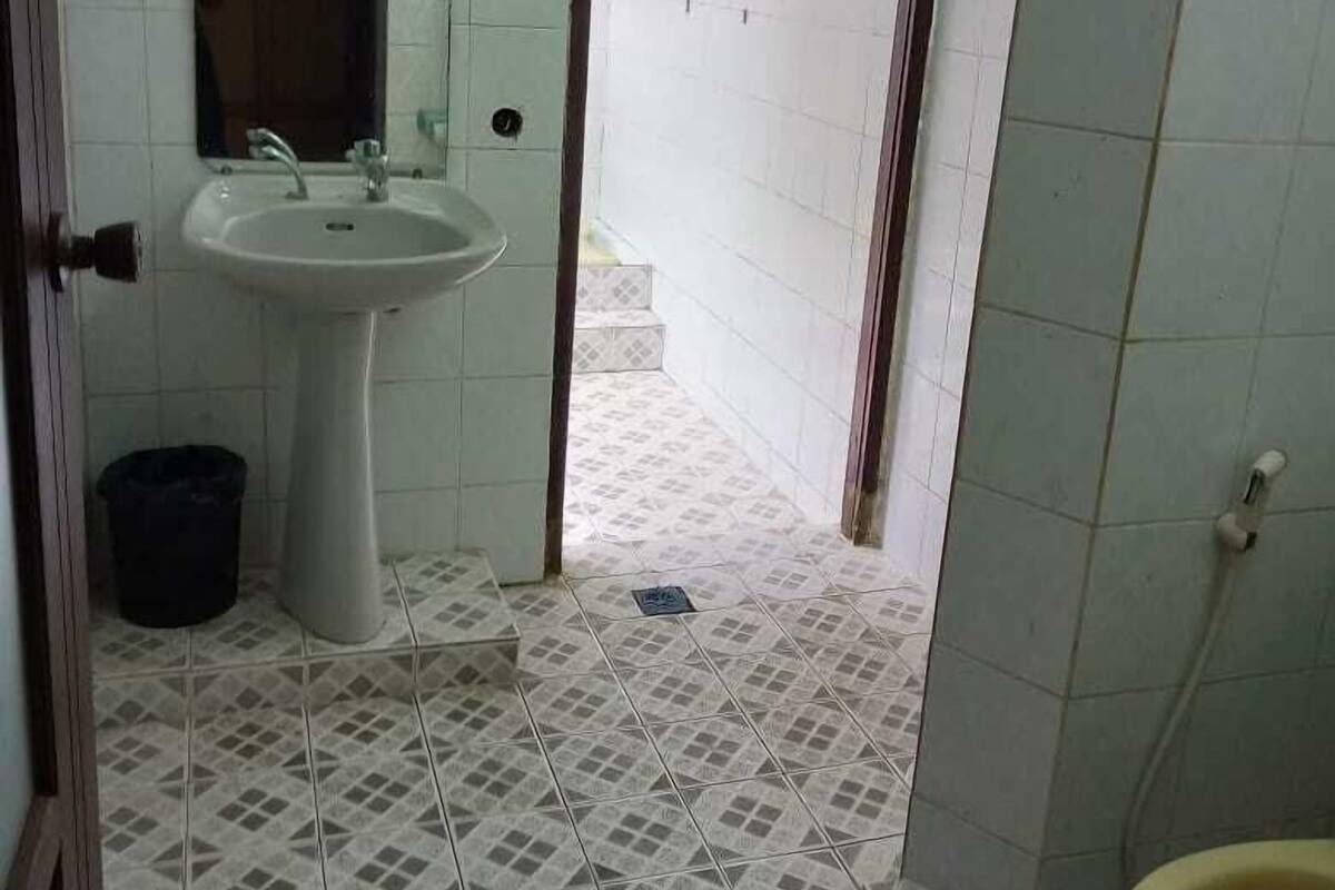 Een badkamer met een wastafel, spiegel, toilet en betegelde vloer.