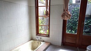 Un baño con bañera, ventana y puerta.