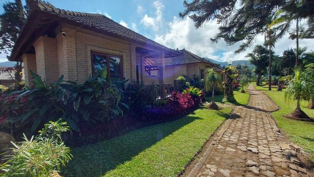 Una casa tradicional con techo de tejas, rodeada de un jardín cuidado con un camino de piedra que lleva a la entrada.
