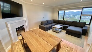 Een moderne woonkamer met een modulaire bank, een houten salontafel en een open haard.