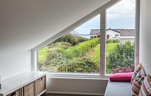 Une pièce dotée d’une grande fenêtre donnant sur un jardin et offrant une vue sur des maisons.
