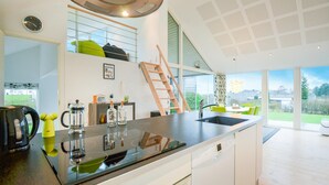 Une cuisine moderne dotée d’un grand îlot central, d’un lave-vaisselle encastré et offrant une vue sur l’extérieur.