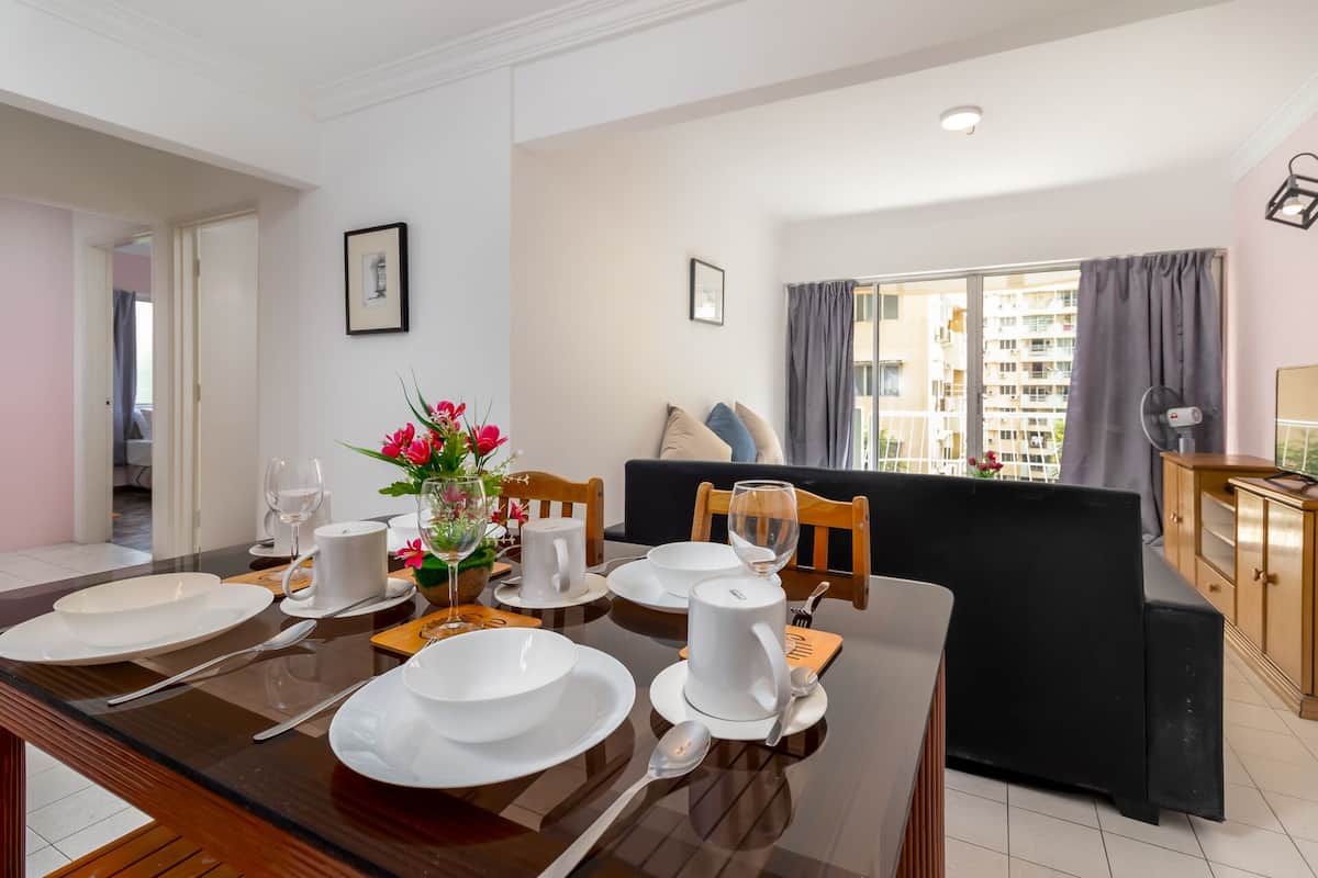 A dining area with a table set for four, a sofa, and a view of a residential building.