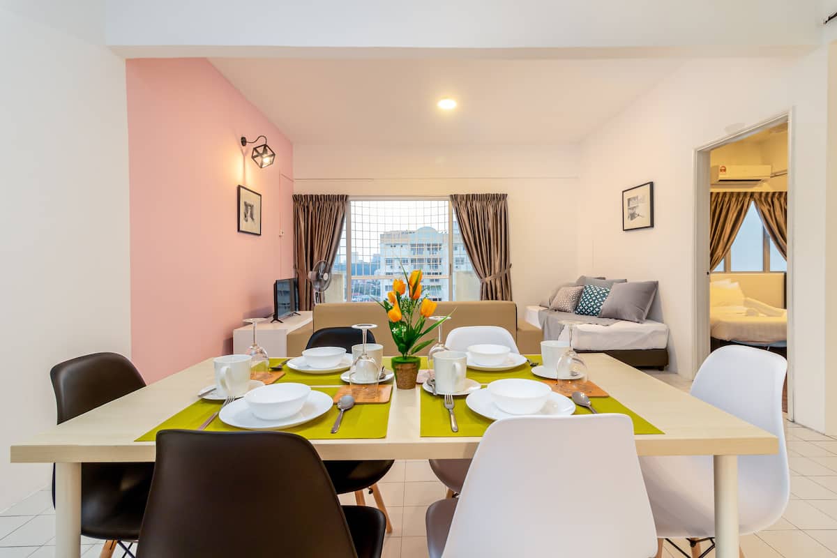 A dining area with a table set for four, a sofa, and a window with curtains.