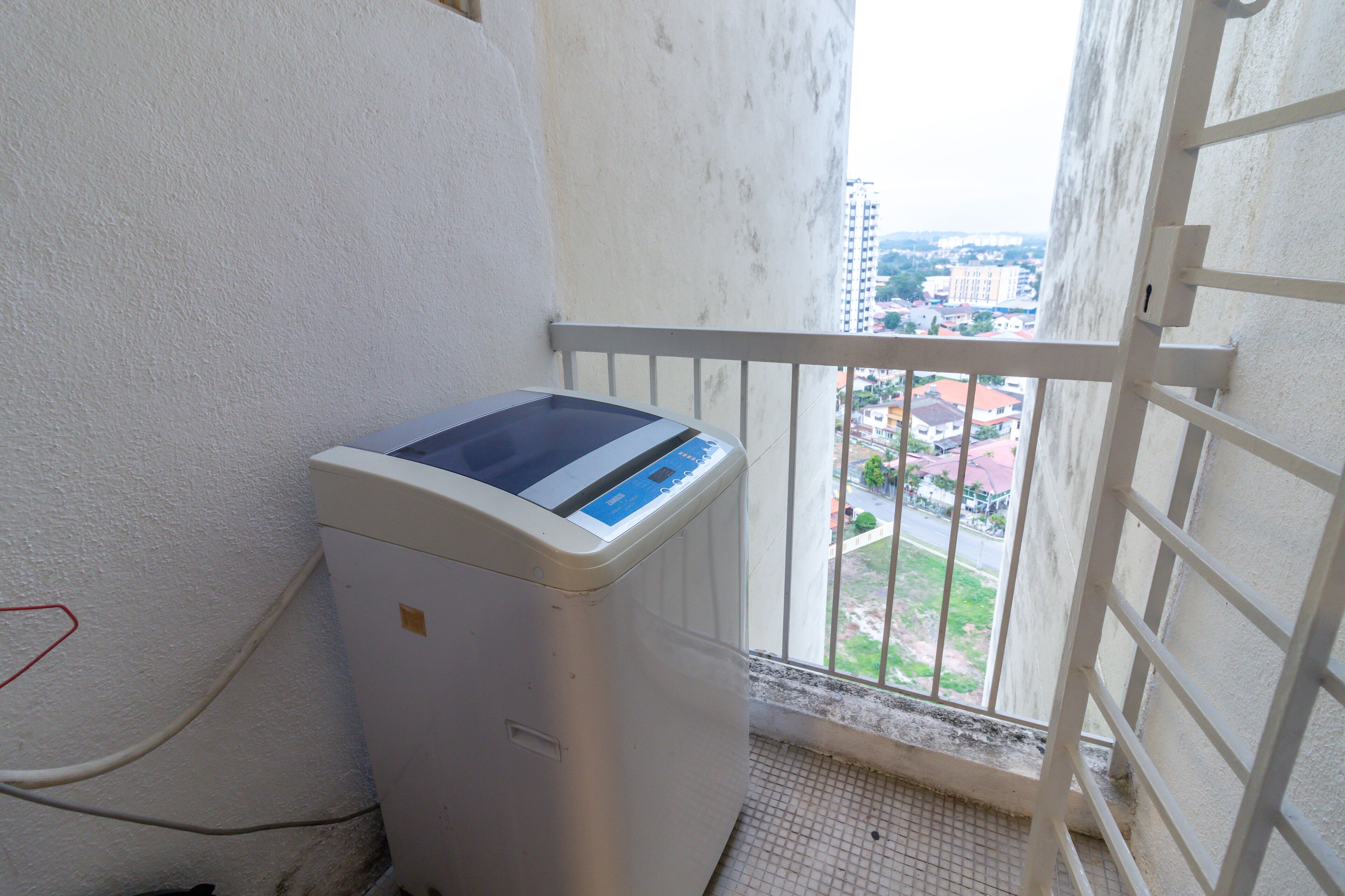 A washing machine in a small balcony area with a view of a cityscape.