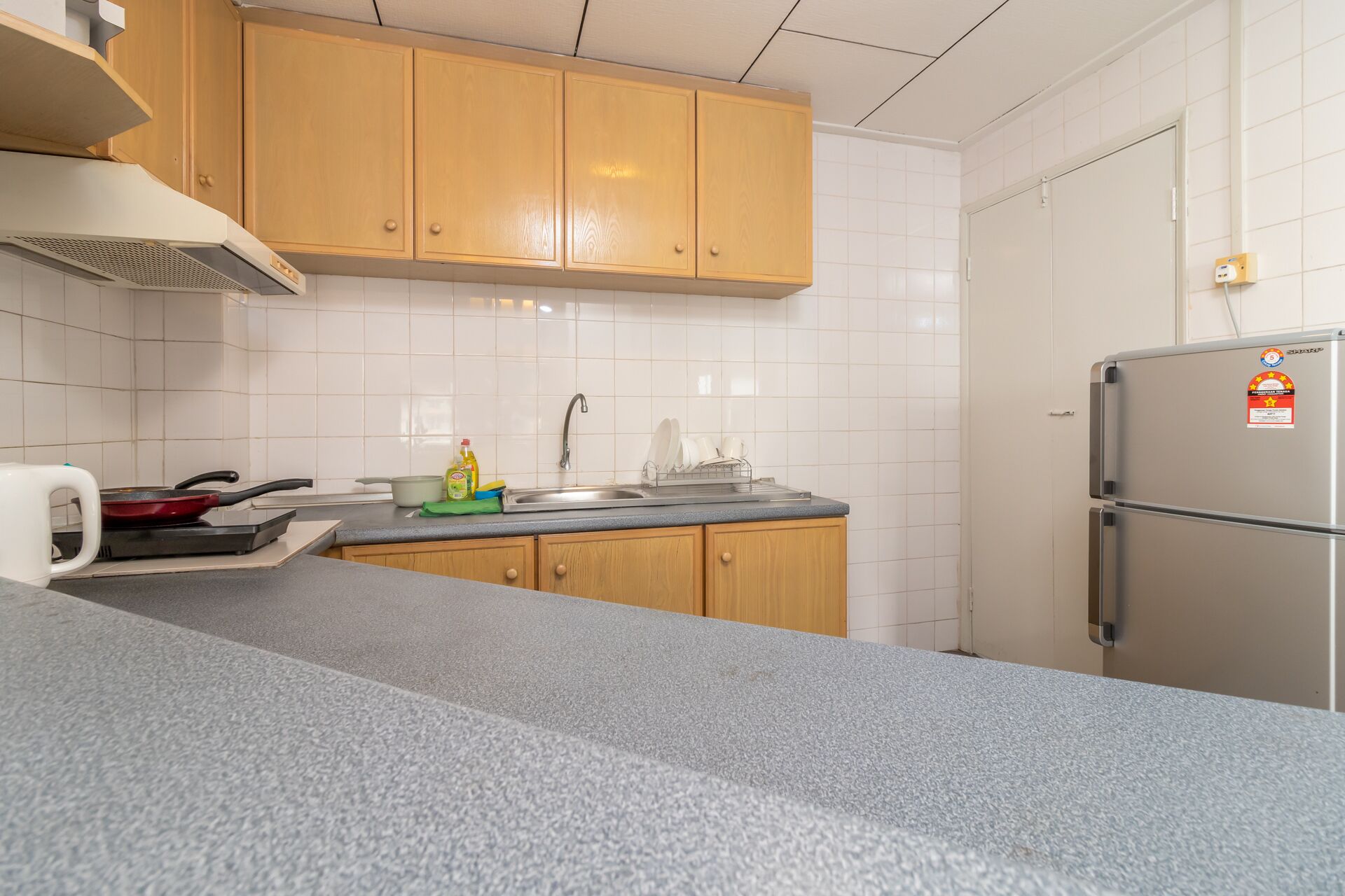 A kitchen with wooden cabinets, a stainless steel refrigerator, a sink, and a stove.