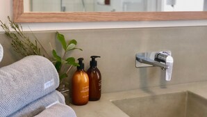 A bathroom with a sink, two hand and body lotion bottles, a towel, and a mirror. - Hakea King Suite- Inlet Waters Escape. Stroll the inlet & nature boardwalk (Inverloch)