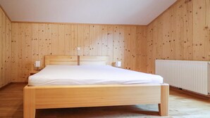 A wooden-paneled bedroom with a single bed, bedside lamps, and a radiator. - moderne Ferienwohnung/Dalaas (Dalaas)