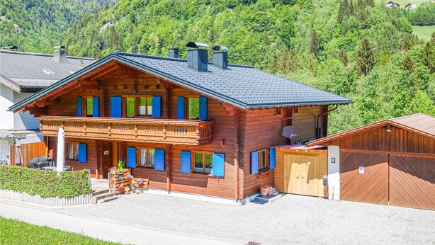 A wooden chalet with a balcony, a garage, and a view of a forested mountain. - moderne Ferienwohnung/Dalaas (Dalaas)