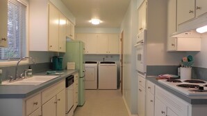 A compact kitchen with white cabinets, a green refrigerator, a sink, and a stove. - Mid-Century Modern w/ Garage Close to Amenities & 3 Miles to Autzen/UO! (Eugene)