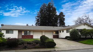 A single-story house with a garage, a driveway, and a well-maintained lawn. - Mid-Century Modern w/ Garage Close to Amenities & 3 Miles to Autzen/UO! (Eugene)
