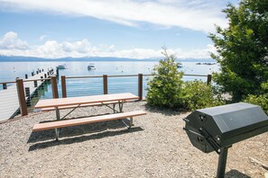 A picnic table and grill by a lake with boats in the background. - Tahoe Park Amenities Elevated Mountain Cabin, Beach, Piers and more (Tahoe City)