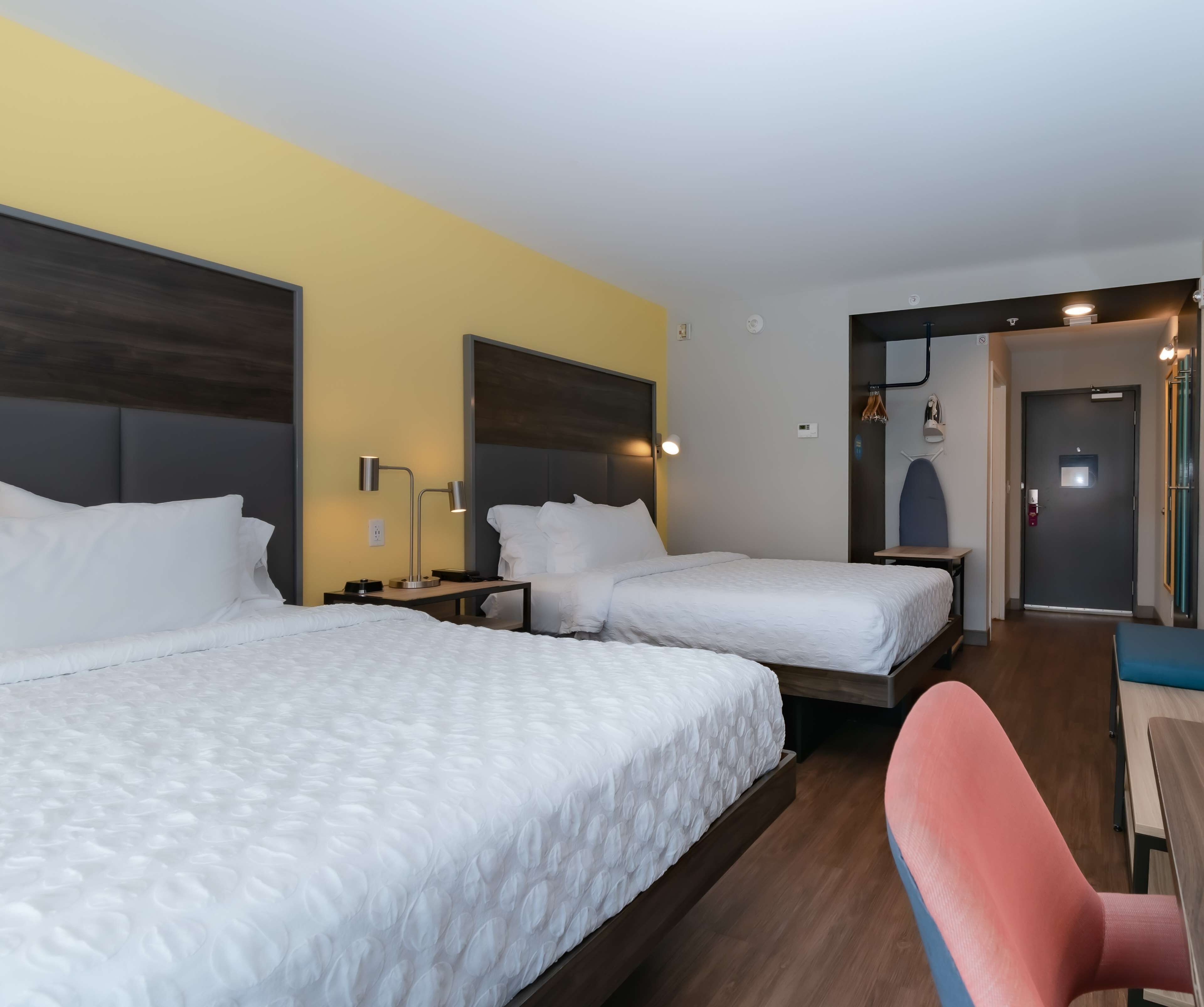 A hotel room with two beds, a desk, a chair, and a wardrobe.