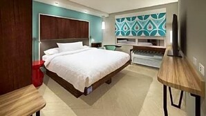 Een hotelkamer met een bed, een bureau, een stoel en een televisie.
