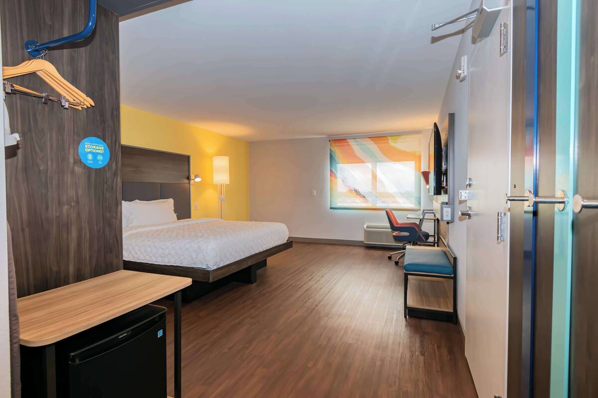 A hotel room with a bed, a desk, a chair, a TV, and a window with a view.