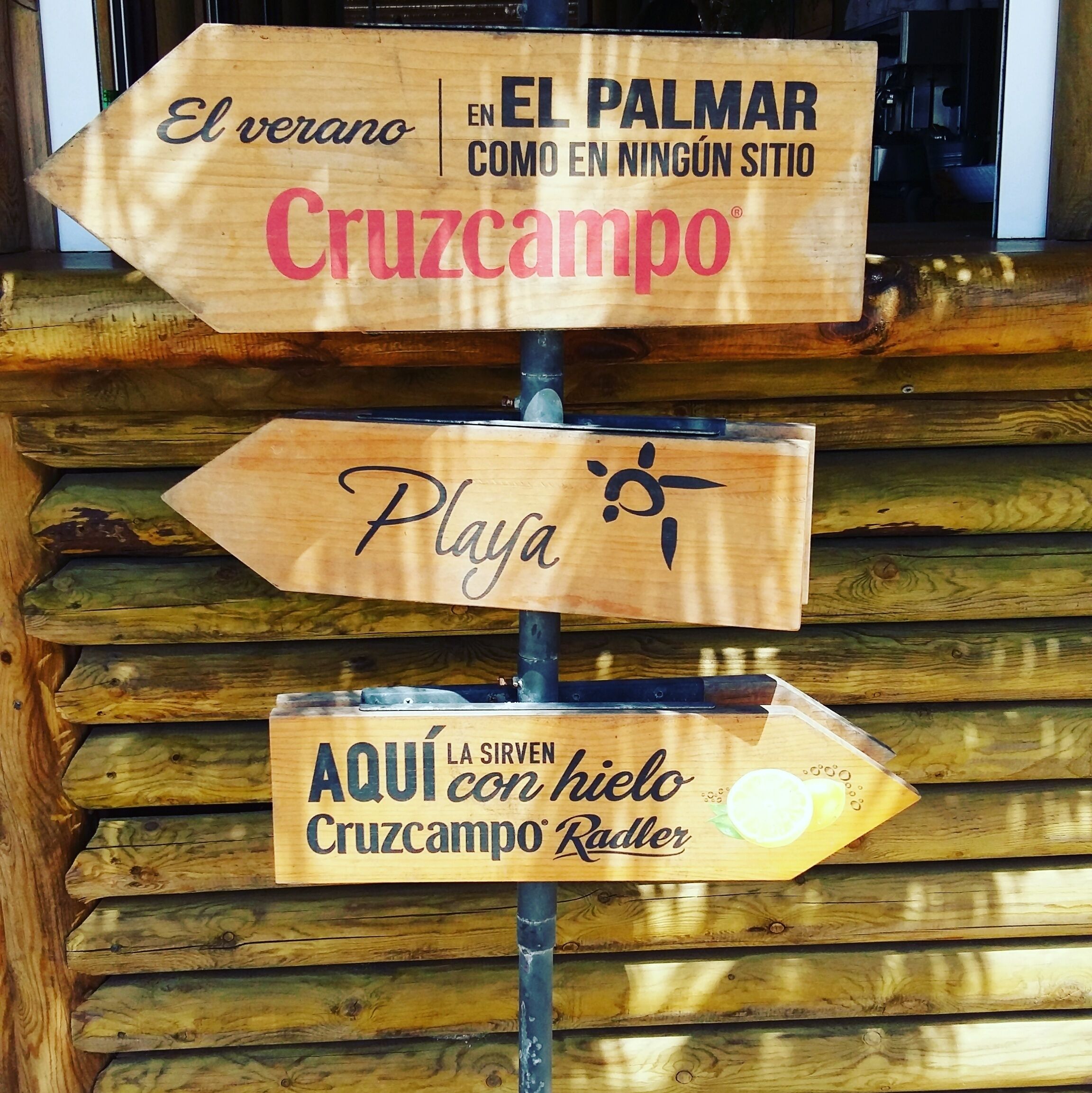 A wooden sign with directional arrows and text indicating locations and amenities.