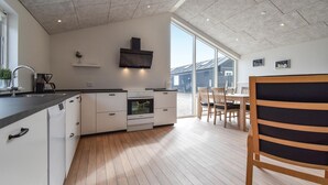 A modern kitchen with white cabinetry, a built-in oven, and a large window offering a view of the outside. - Lovely home in Nyborg (Nyborg)