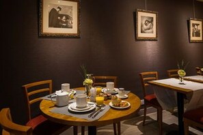 Un comedor con mesas redondas, sillas e imágenes enmarcadas en la pared.