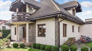 Une maison à deux étages avec une façade en pierre, un balcon et un toit recouvert de tuiles.
