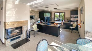Une cuisine moderne dotée d’un îlot central, d’un coin repas avec des chaises à motifs et d’une cheminée.