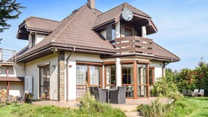 Une maison à deux étages, avec un toit en tuiles, un balcon et une antenne parabolique.