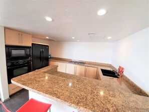 A modern kitchen with granite countertops, built-in appliances, and a red chair. - Viewtastic! (Phoenix)