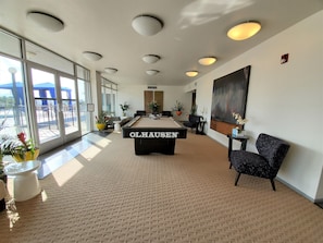 A billiards room with a pool table labeled "OLHAUSEN," large windows, and potted plants. - Viewtastic!! (Phoenix)