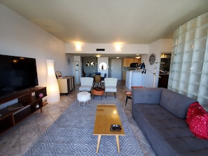 A living room with a flat-screen TV, a sofa, a coffee table, and patterned rugs. - Viewtastic!! (Phoenix)
