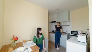 Una cucina compatta con mobili bianchi, un forno a microonde e un piccolo frigorifero.