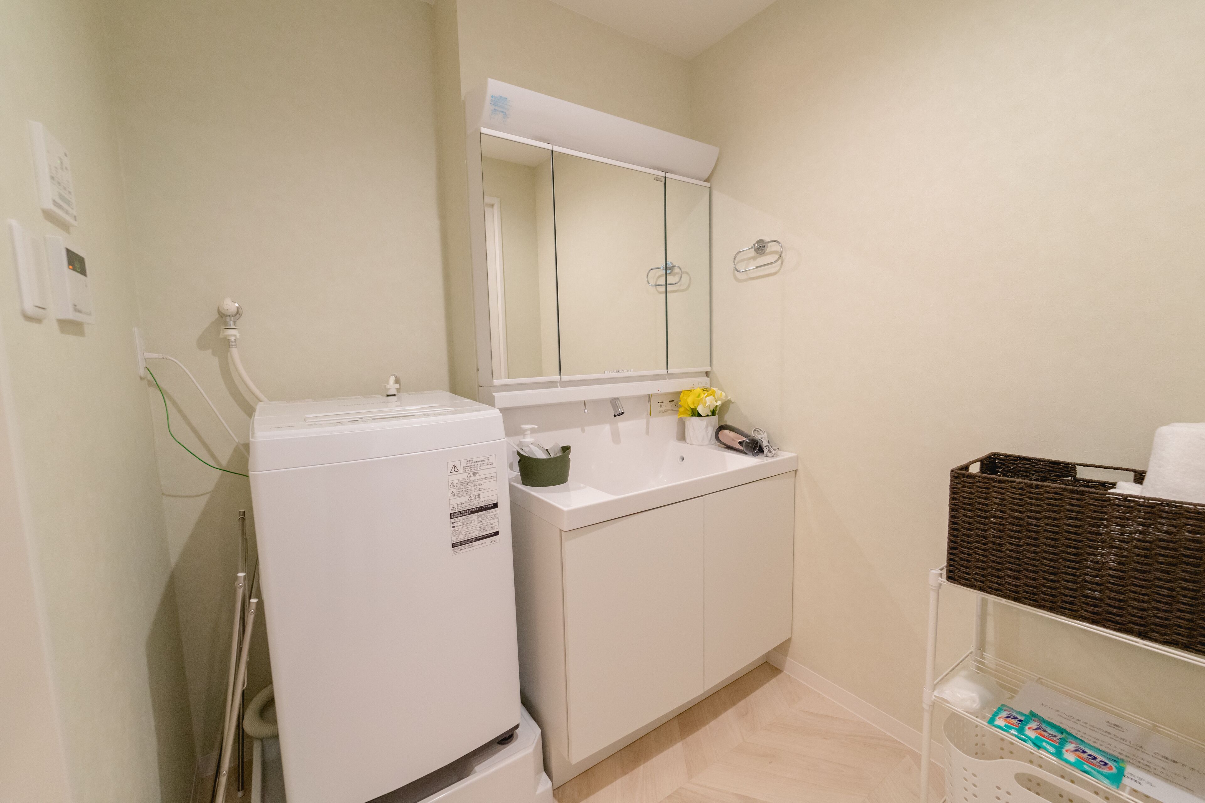 A small bathroom with a white washing machine, a sink, and a mirror above it.