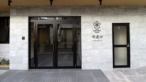 Une entrée moderne, avec une porte en verre et une enseigne indiquant « Sakairo Kyoto Tandabuguchi ».