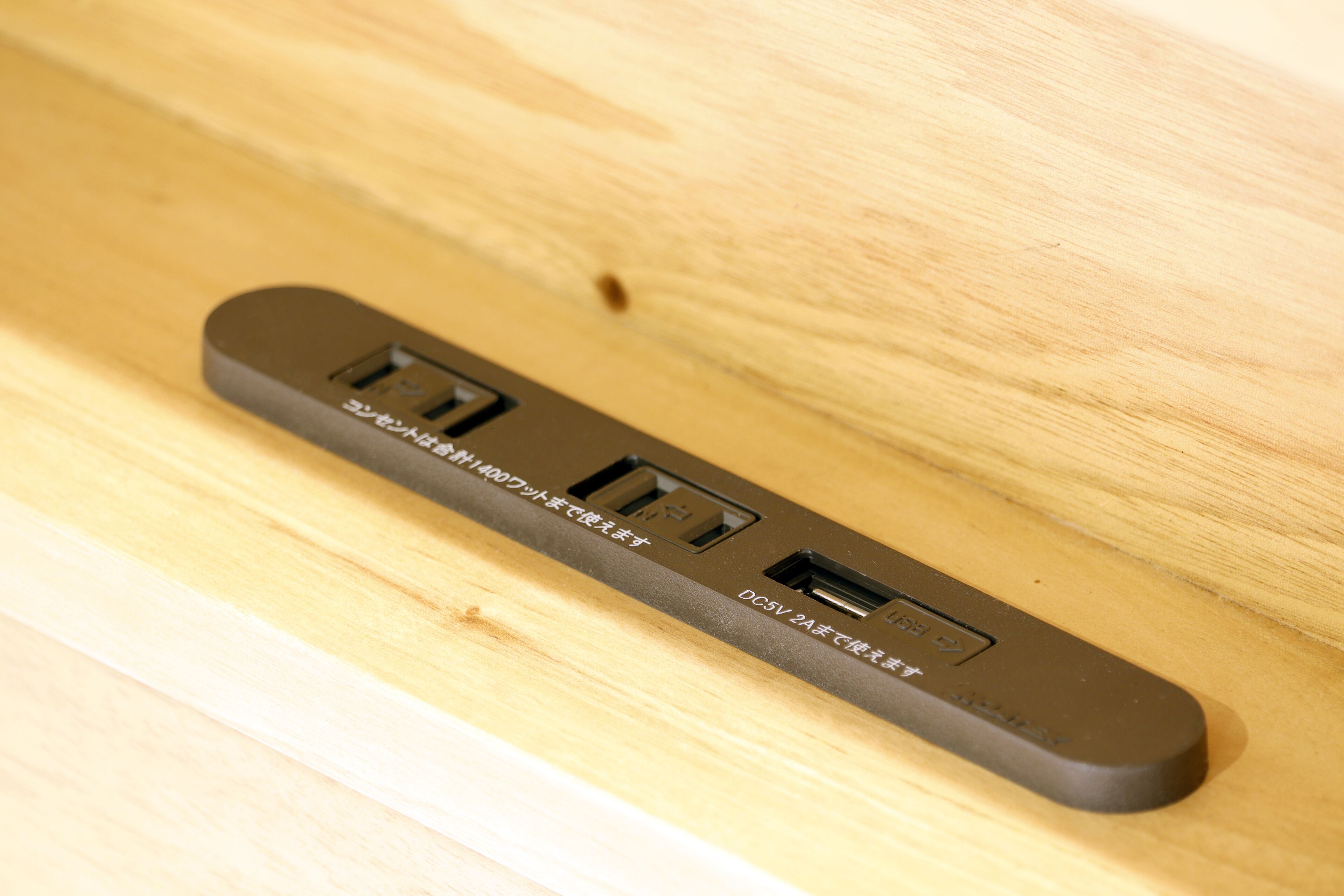A power strip with multiple USB ports and an Ethernet port on a wooden surface.