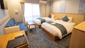 Une chambre d’hôtel avec deux lits, un canapé, une petite table et un téléviseur.