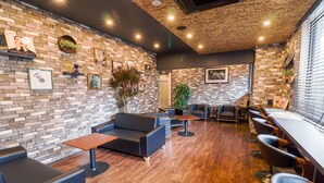 Un espace de détente moderne avec des murs en briques, un plancher en bois et différents types de sièges, notamment des canapés et des tabourets de bar.