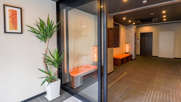 Un hall d’hôtel moderne avec un comptoir d’accueil, un espace salon et une grande plante en pot.