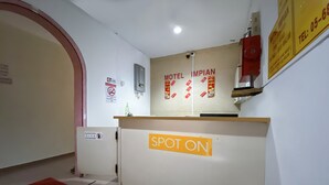 Un comptoir d’accueil avec une enseigne indiquant « MOTEL IMPIAN » et, en dessous, une autre enseigne indiquant « SPOT ON ».